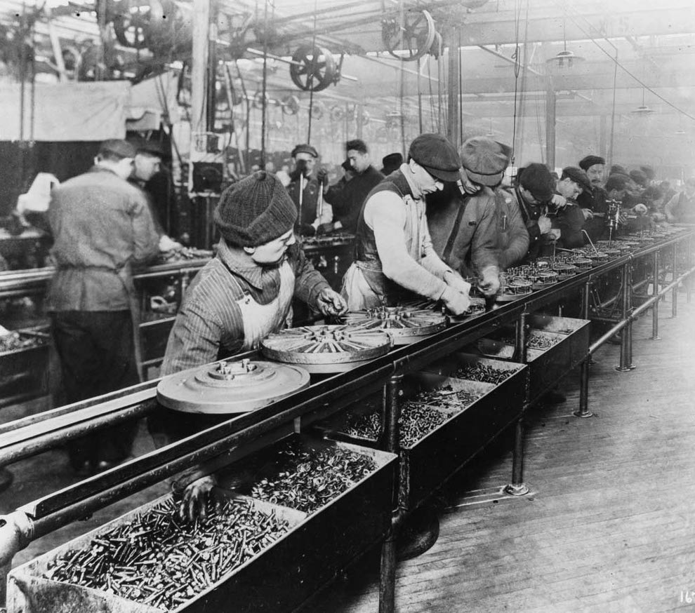 "Workers on the first moving assembly line put together magnetos and flywheels for 1913 Ford autos" Highland Park, Michigan (Public Domain via Wikimedia Commons)