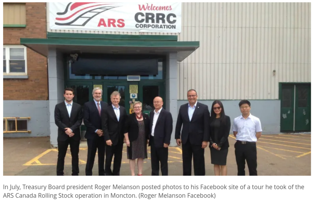 A photo of people standing in front of the ARS Rolling Stock Canada facility in Moncton.