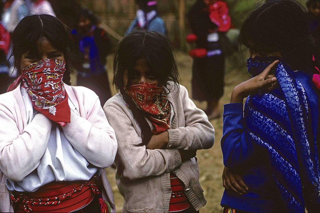A photo of three girls with scarves hiding their faces.